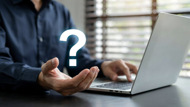 Business professional sitting at desk using laptop with a floating question mark icon question business solution customer computer technology confusion analysis information professional