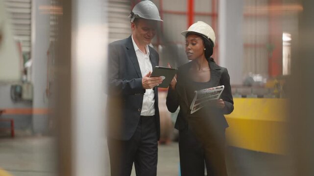 Industrial entrepreneur and a female manager or engineer collaborate inside a modern factory, discussing factory expansion or inspecting production systems, assessing machinery condition, discussing