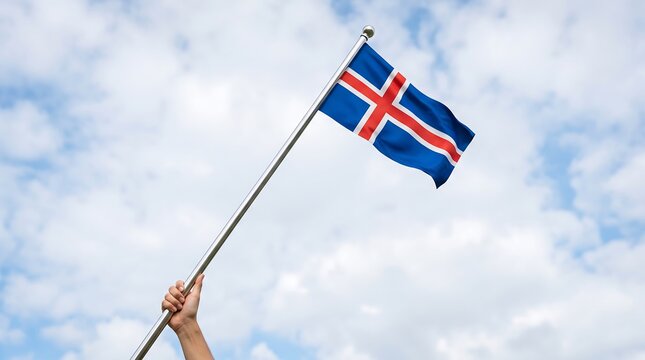 Hand holding Icelandic national flag on silver pole against bright blue sky with scattered clouds