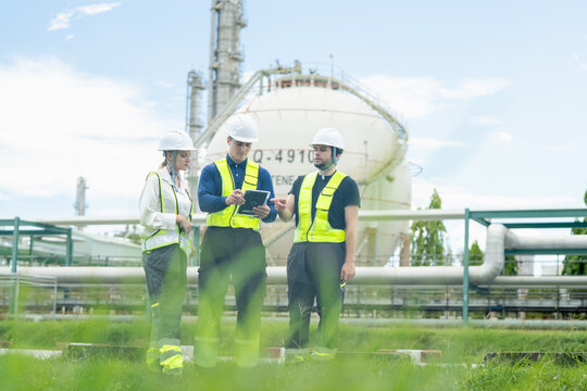 Team of industrial workers working together at a chemical facility wearing safety gear and using specialized equipment