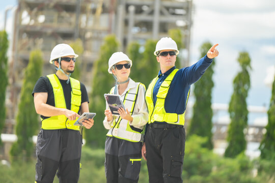 Team of construction professionals working together on site wearing safety equipment and utilizing technology for effective project management