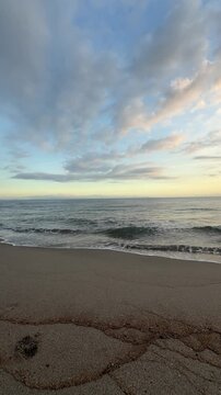 Peaceful sunset beach landscape with waves and cloudy sky.