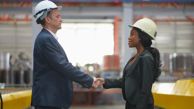 Partners in the manufacturing industry shake hands in the factory to discuss the purchase of machinery, procurement of goods, or discussions about increasing investment in factory technology machinery