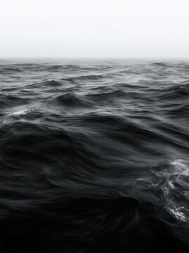 Dark ocean waves beneath a pale foggy horizon