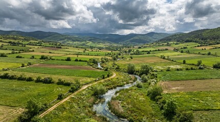 Fototapeta premium Aerial view of green farmland and hills. Rural landscape with a winding river and fields.