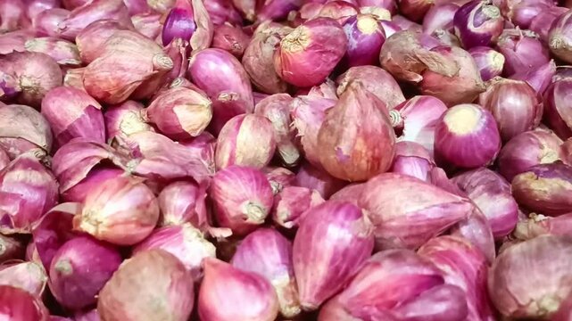 Fresh red shallots and onions piled in a market, showcasing raw organic ingredients for cooking healthy meals.