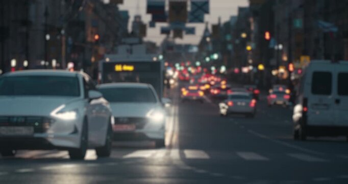 Defocused evening traffic moving through a busy urban street with glowing headlights and city lights.