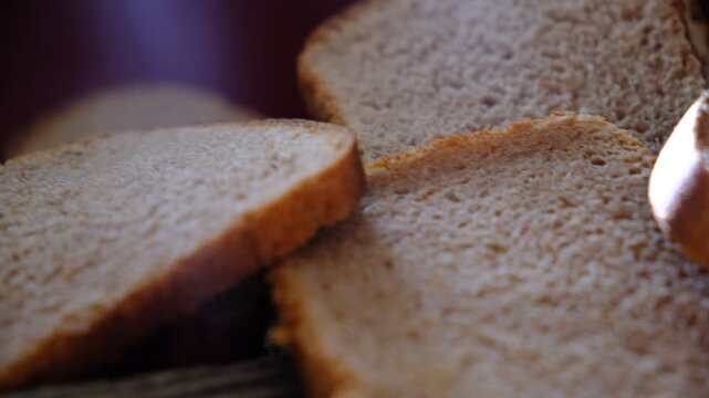 Sliced fresh rye bread on textured golden brown wooden background. Healthy wholemeal bread slices. Dark background