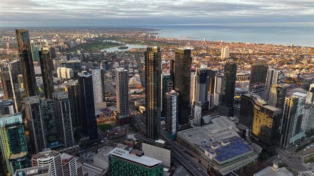 Aerial drone video of Southbank at sunrise, revealing Albert Park Lake and Port Phillip Bay beyond Melbourne&rsquo;s skyscrapers and city streets