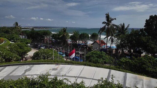 Aerial view of Kuta Beach with waves, palms and beachfront traffic in Bali