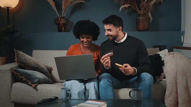 Young Couple Shopping and buying Online With Credit Card on Sofa Together at home at night
