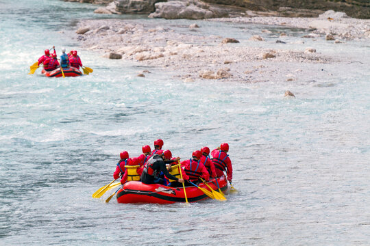Whitewater rafting teams navigate down a turquoise mountain Fella river, experiencing adventure and outdoor tourism lifestyle in the Julian Alps Natural Park, Resia, Friuli Venezia Giulia, Italy.