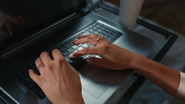 Female hands typing on laptop keyboard with coffee nearby daytime actively pressing keys and working on computer in home environment