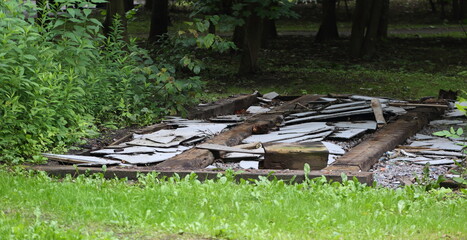 The wooden foundation of an old dismantled barn in a green meadow © Станислав Вершинин