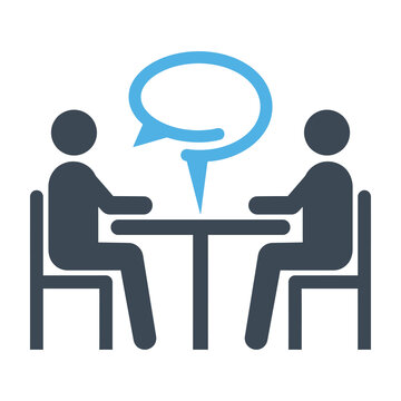 Two people sitting at a table talking and communicating
