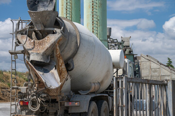 Naklejka premium a white concrete mixer truck parked in front of three tall green storage silos at an industrial concrete batching plant