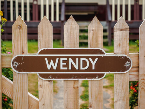 Brown and white name plate of Wendy on garden picket gate