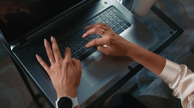 Female hands typing on laptop keyboard at glass table daytime close up workflow remote work and everyday activity