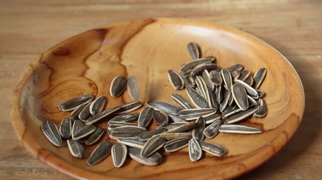 Slow motion footage of sunflower seeds dropping on the wooden table