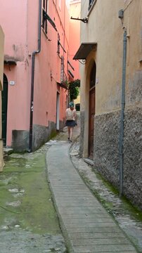 Cervo, liguria, italy. June 22, 2025. Young tourist walking through a typical narrow street in the ancient village of cervo. Picturesque old town in liguria, italian riviera