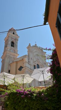 Cervo, liguria, italy. June 22, 2025. Sun shining on the beautiful baroque facade and bell tower of the church of saint john the baptist in the medieval village of cervo, liguria