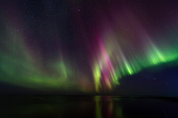 Bight and intense Northern Lights Aurora Borealis in the dark night sky above Iceland and the Atlantic Ocean © Richard Waghorn