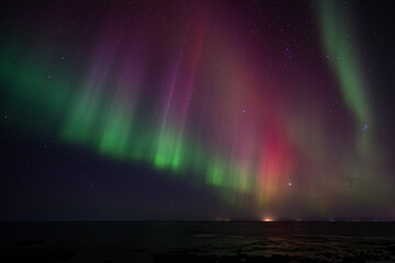 Bight and intense Northern Lights Aurora Borealis in the dark night sky above Iceland and the Atlantic Ocean © Richard Waghorn