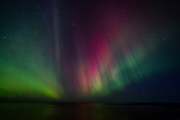 Bight and intense Northern Lights Aurora Borealis in the dark night sky above Iceland and the Atlantic Ocean © Richard Waghorn
