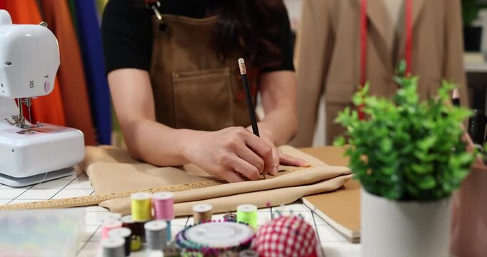 Fashion designer creating garment patterns, measuring fabric, inspecting clothing quality, and preparing apparel in a professional studio for tailoring, production, and fashion design workflow.