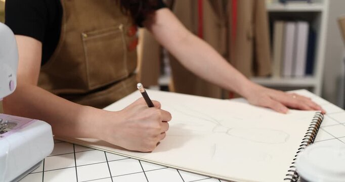 Fashion designer creating garment patterns, measuring fabric, inspecting clothing quality, and preparing apparel in a professional studio for tailoring, production, and fashion design workflow.