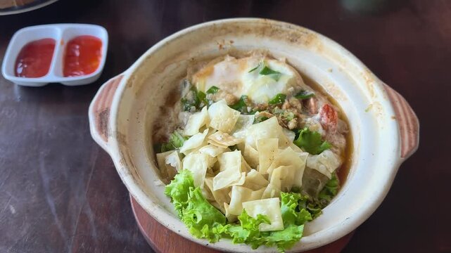 Delicious savory food served in a rustic ceramic pot with fresh greens and a side of dipping sauce ready for a satisfying meal experience during a casual dining occasion
