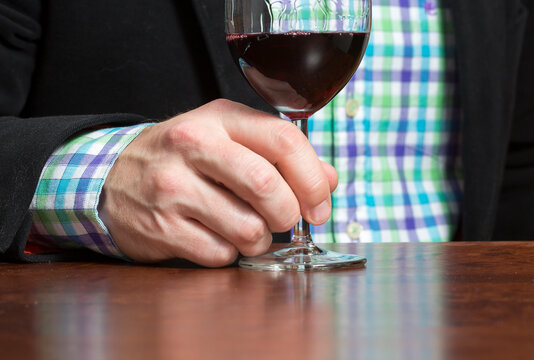Caucasian man is enjoying a glass of red wine. Business outfit.