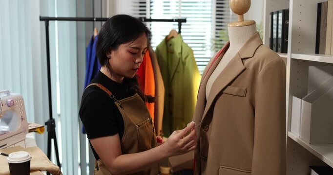 Fashion designer creating garment patterns, measuring fabric, inspecting clothing quality, and preparing apparel in a professional studio for tailoring, production, and fashion design workflow.