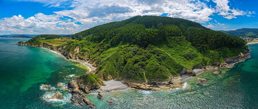 Costa Verde Spain - Aerial view of Forest Rolling into the Atlantic Ocean with green vegetation pouring on to wild beach coast surrounded by rocky cliffs