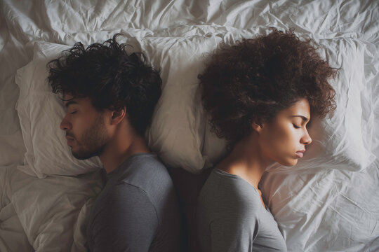 A photograph depicting an angry couple in bed, facing away from each other.