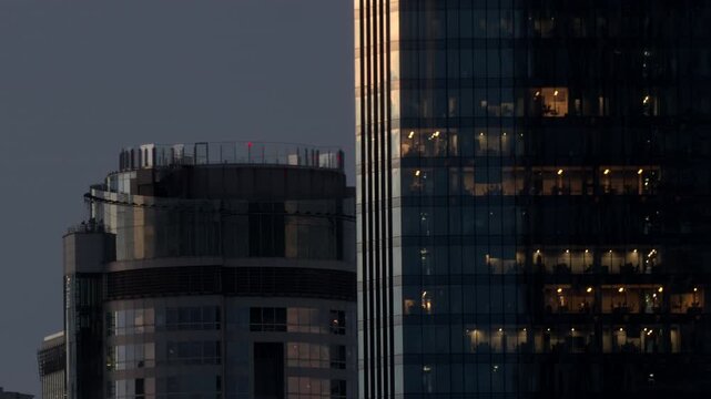 Modern office skyscraper buildings business district interior window lights night. High angle view showing illuminated glass windows