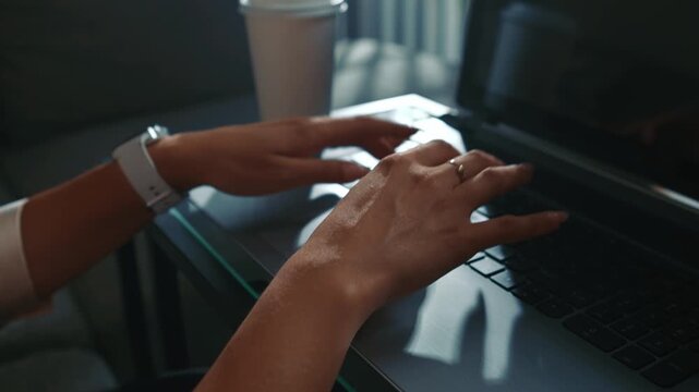 Woman hands typing on laptop at home with coffee close up daytime focused entering text and completing tasks in a calm home environment
