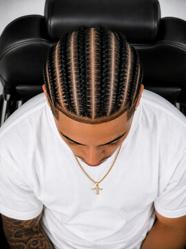 Man with braided hairstyle sitting in a barber chair