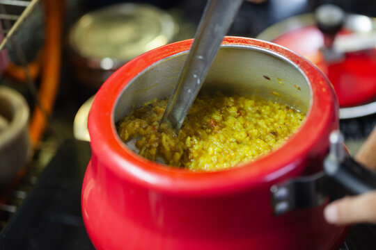Freshly cooked Indian khichdi served in a ladle inside pressure cooker