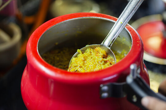 Freshly cooked Indian khichdi served in a ladle inside pressure cooker