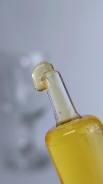 Honey yellow cream melting and dripping from the tip of transparent product packaging. Natural skincare extract concept for beauty treatment.