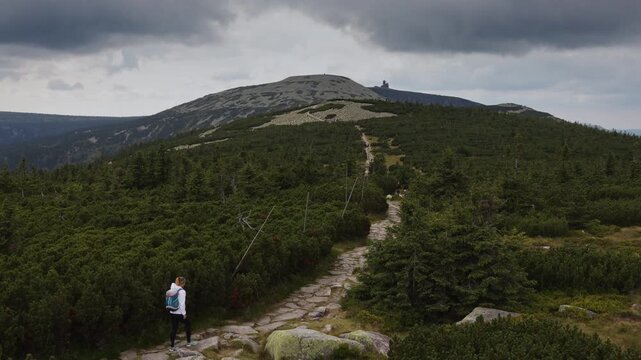 Aerial view of a woman hiking a mountain trail towards Snezne Jamy and Silesian Stones ridge in Krkonose, Czech Republic