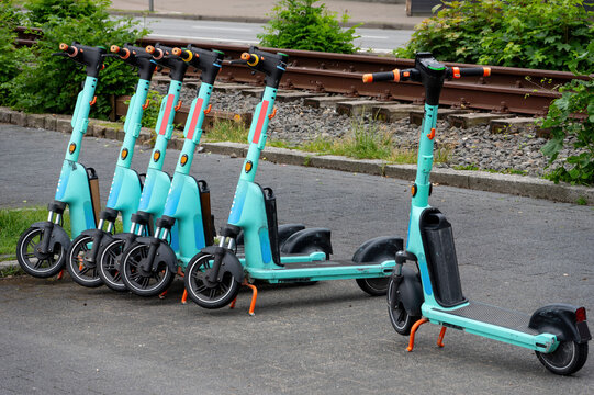 Shared electric scooters parked beside railway tracks in an urban environment