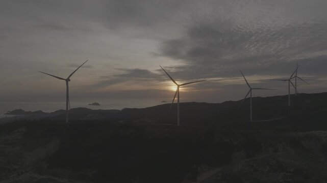 Aerial drone footage of sunrise over Ky Mountain Wind Farm near Quy Nhon, Gia Lai, Vietnam, featuring coastal scenery, wind turbines, golden morning light and renewable energy.