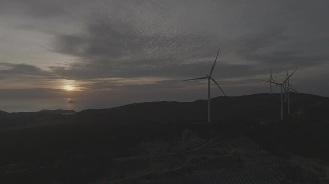 Aerial drone footage of sunrise over Ky Mountain Wind Farm near Quy Nhon, Gia Lai, Vietnam, featuring coastal scenery, wind turbines, golden morning light and renewable energy.