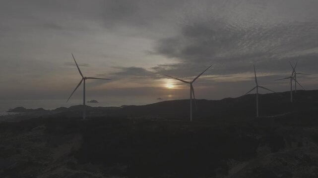 Aerial drone footage of sunrise over Ky Mountain Wind Farm near Quy Nhon, Gia Lai, Vietnam, featuring coastal scenery, wind turbines, golden morning light and renewable energy.