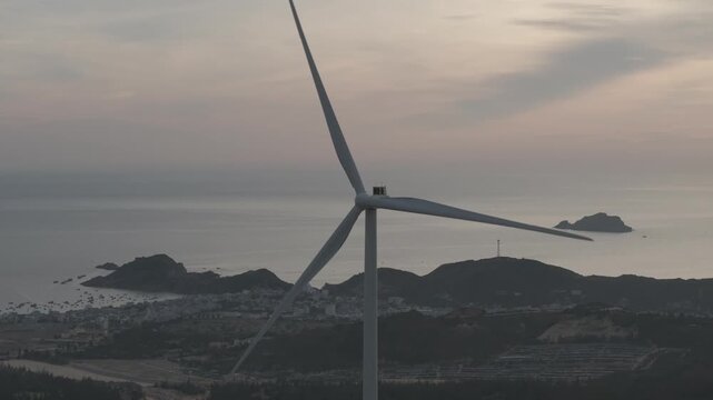 Aerial drone footage of sunrise over Ky Mountain Wind Farm near Quy Nhon, Gia Lai, Vietnam, featuring coastal scenery, wind turbines, golden morning light and renewable energy.
