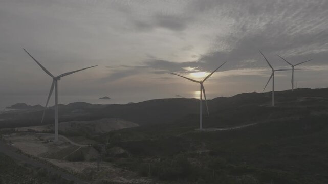 Aerial drone footage of sunrise over Ky Mountain Wind Farm near Quy Nhon, Gia Lai, Vietnam, featuring coastal scenery, wind turbines, golden morning light and renewable energy.