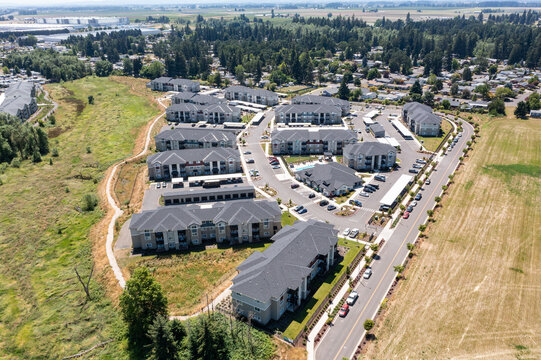 Aerial drone photo of residential neighborhoods and modern apartment communities in Woodburn, Oregon, USA surrounded by farmland and suburban development near Interstate 5