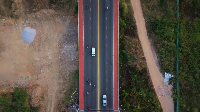 Vertical drone view of vehicles crossing a modern bridge with surrounding green landscape in central Vietnam.